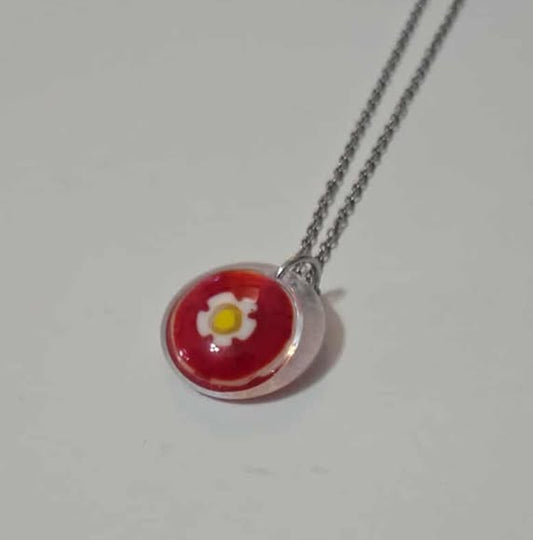 Necklace with a round pendant featuring a red flower design on a white background